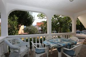 a white porch with a table and chairs on it at Apartments Nadenic in Šilo