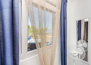 a window with blue curtains and a fan at House Green Oasis in Vodice