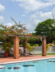 una piscina con pérgola y un patio con flores en Hotel Santa Isabel, en Pereira