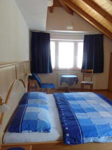 Schlafzimmer mit einem blauen und weißen Bett und einem Fenster in der Unterkunft Appartamenti Valpinoi in St. Christina in Gröden