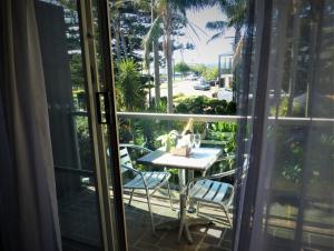 a table and chairs on a balcony with a view of a street at Park Ridge Retreat in Gerringong