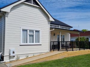 a white house with a porch and a fence at The Heart of Hastings in Hastings