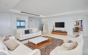 a living room with white furniture and a flat screen tv at Soul Surfers Paradise - GCLR in Gold Coast
