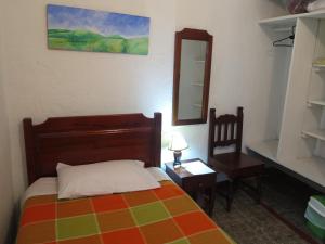 a bedroom with a bed and a mirror and a chair at Hostal La Cazihita in Sogamoso