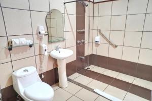 a bathroom with a toilet, sink and mirror at La Quinta Sarapiqui Lodge in Sarapiquí