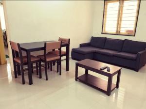 uma sala de estar com um sofá, uma mesa e cadeiras em Chippy Apartments 3006B em Chennai