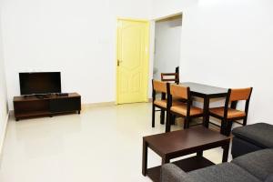 Una sala de estar con una mesa y sillas y un televisor. en Chippy Apartments 3006B, en Chennai