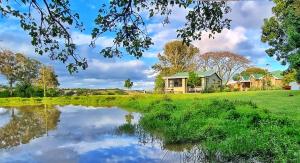 une maison à côté d'un étang devant une maison dans l'établissement OppiePlaas Country Estate, à Haga-Haga