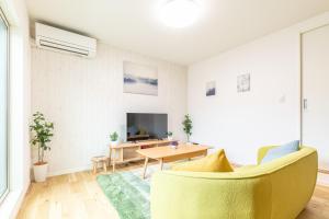 salon z żółtą kanapą i telewizorem w obiekcie Pau-lele天下茶屋東 w Osace