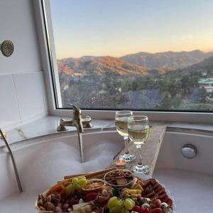 a plate of food and wine glasses in a bath tub at Aprosmeno Jacuzzi House 1 in Agros