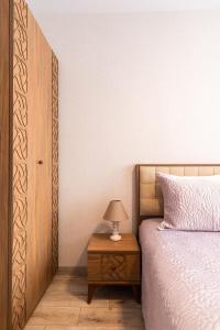 ein Schlafzimmer mit einem Bett und einem Tisch mit einer Lampe in der Unterkunft Central Point Premium + in Ruse