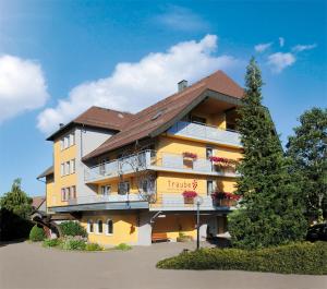 ein großes gelbes Gebäude mit Blumen auf den Balkonen in der Unterkunft Hotel Traube Lossburg in Loßburg