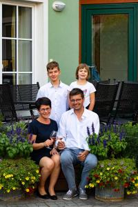 a group of people sitting on a bench in front of a house at Weingut Familie Bauer in Großriedenthal