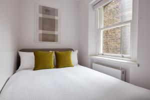 a bedroom with a white bed with yellow pillows at 5VH Virginia House, 31 Bloomsbury Way in London