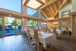 a dining room with white tables and chairs and windows at Alpenresort Eienwäldli Engelberg in Engelberg