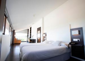 ein Schlafzimmer mit einem großen weißen Bett in einem Zimmer in der Unterkunft Hotel Rural Las Monteras in Villanueva del Rey