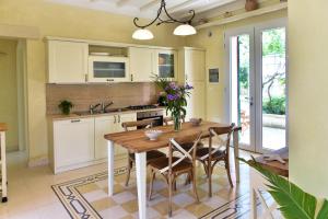eine Küche mit einem Holztisch und einigen Stühlen in der Unterkunft Villa Sirgole Rosa with Pool, Galatina in Cutrofiano