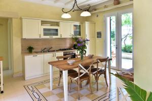 a kitchen with a wooden table and some chairs at Villa Sirgole Rosa with Pool, Galatina in Cutrofiano