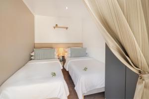 two beds in a room with white walls and curtains at Waterman Beach Village in Supetar