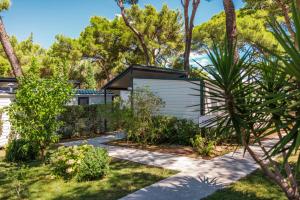 a garden with a white building with a black roof at Waterman Beach Village in Supetar
