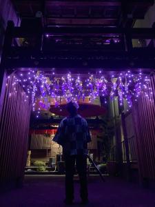 un hombre parado en una habitación con luces púrpuras en Benidaruma - Yatsuhashi, en Kioto