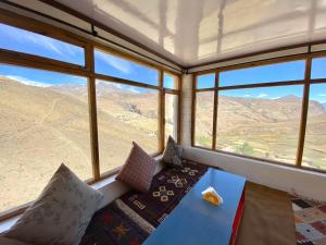 a room with a couch and a table and windows at Tethys Himalayan DEN - Chicham in Kaza