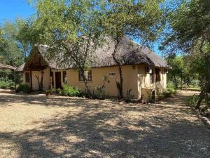 an old house with a thatched roof and a yard at Lituba Place in Marloth Park