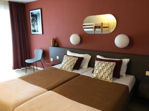 ein Hotelzimmer mit einem großen Bett und einem Spiegel in der Unterkunft Résidence Les Baladines in Thonon-les-Bains