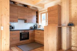 een keuken met houten kasten en een fornuis bij Holiday village Koralpe St- Stefan im Lavanttal - OKT07003-FYC in Elsenbrunn