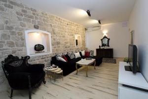 uma sala de estar com mobiliário preto e uma parede de tijolos em Apartment Papalić Palace em Split