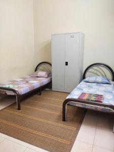 two beds sitting in a room with a locker at Kayu Merbau Homestay in Seri Iskandar