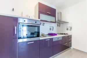 uma cozinha com armários roxos e um lavatório em Apartman Miami Podstrana em Podstrana