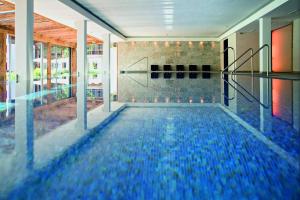 a swimming pool with blue water in a building at Kitzhof Mountain Design Resort 4 Sterne Superior in Kitzbühel