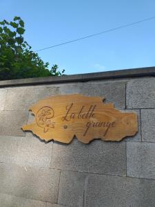 un cartello di legno sul lato di un muro di mattoni di La belle grange a Saint-Étienne-au-Mont