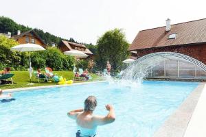 a man in a swimming pool with a fountain at Holiday Village Schlierbach in Schlierbach