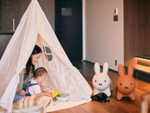 a woman and a baby sitting in a tent at 41 PIECES Sapporo in Sapporo