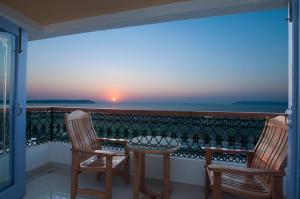 two chairs and a table on a balcony with a sunset at Varanda Do Mar in Panaji