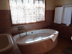 a bath tub in a bathroom with a sink at Lituba Place in Marloth Park +24 photos