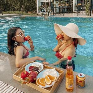 two women eating fruit in the swimming pool at Dream Villas Thạch Thất Venuestay in Hanoi