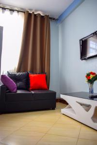 a living room with a black couch and a window at The Adrace Exec. Hotel in Kampala