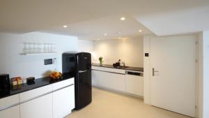 a black refrigerator in a kitchen with white cabinets at Alte Metzg - Hostel in Appenzell