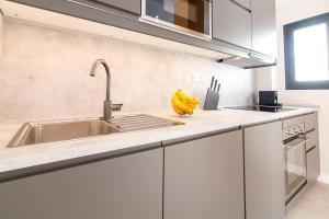 a kitchen with white cabinets and a sink at GRUND SUITES GALLERY by FreshApartments in Málaga +94 photos