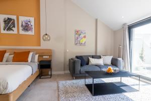 a bedroom with a bed and a couch and a table at GRUND SUITES GALLERY by FreshApartments in Málaga