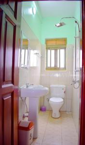 a bathroom with a white toilet and a sink at The Adrace Exec. Hotel in Kampala