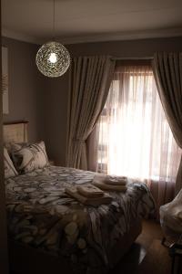 a bedroom with a bed with a window and a chandelier at Locust Retreat Immaculate 2bedroom cottage in Marloth Park