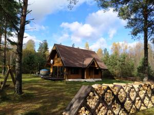 eine Blockhütte im Wald mit einem Zaun in der Unterkunft Trakų vienkiemis in Daumilai