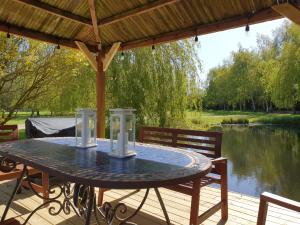 a table on a deck with a view of a lake at Pondside Barn in Long Wittenham