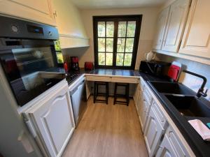 a kitchen with white cabinets and black appliances at Chalet les falaises in Saint-Léonard
