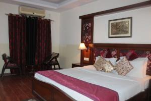 a bedroom with a large bed with red curtains at Hotel New Empire in New Delhi