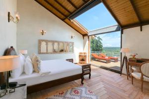 a bedroom with a bed and a large window at Amritara Aura Resort & Spa in Mandrem